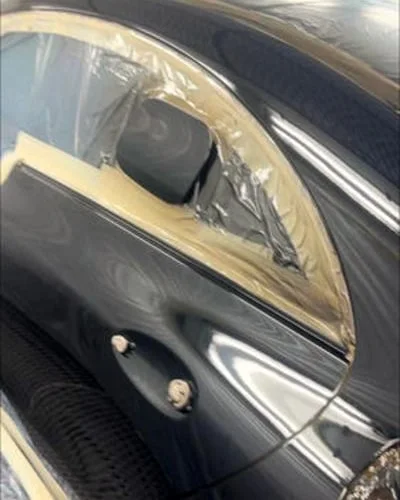 Präzise Fahrzeugvorbereitung mit Abdeckfolie und Klebeband vor der Lackierung.
